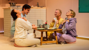 En familj sitter vid ett dukat bord. Alla sitter på golvet och är väldigt glada.